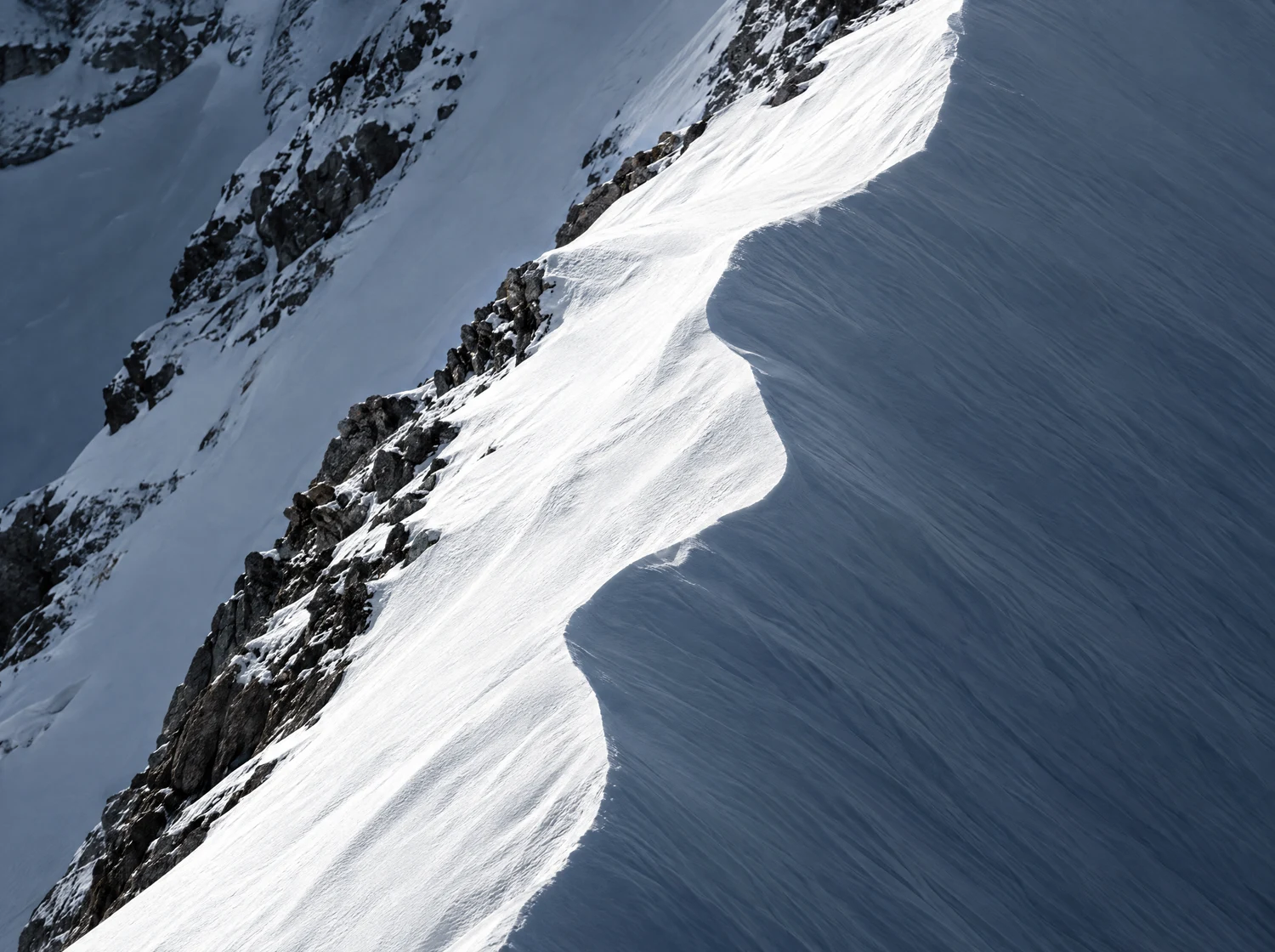 A wind-sculpted snow ridge in the Alps